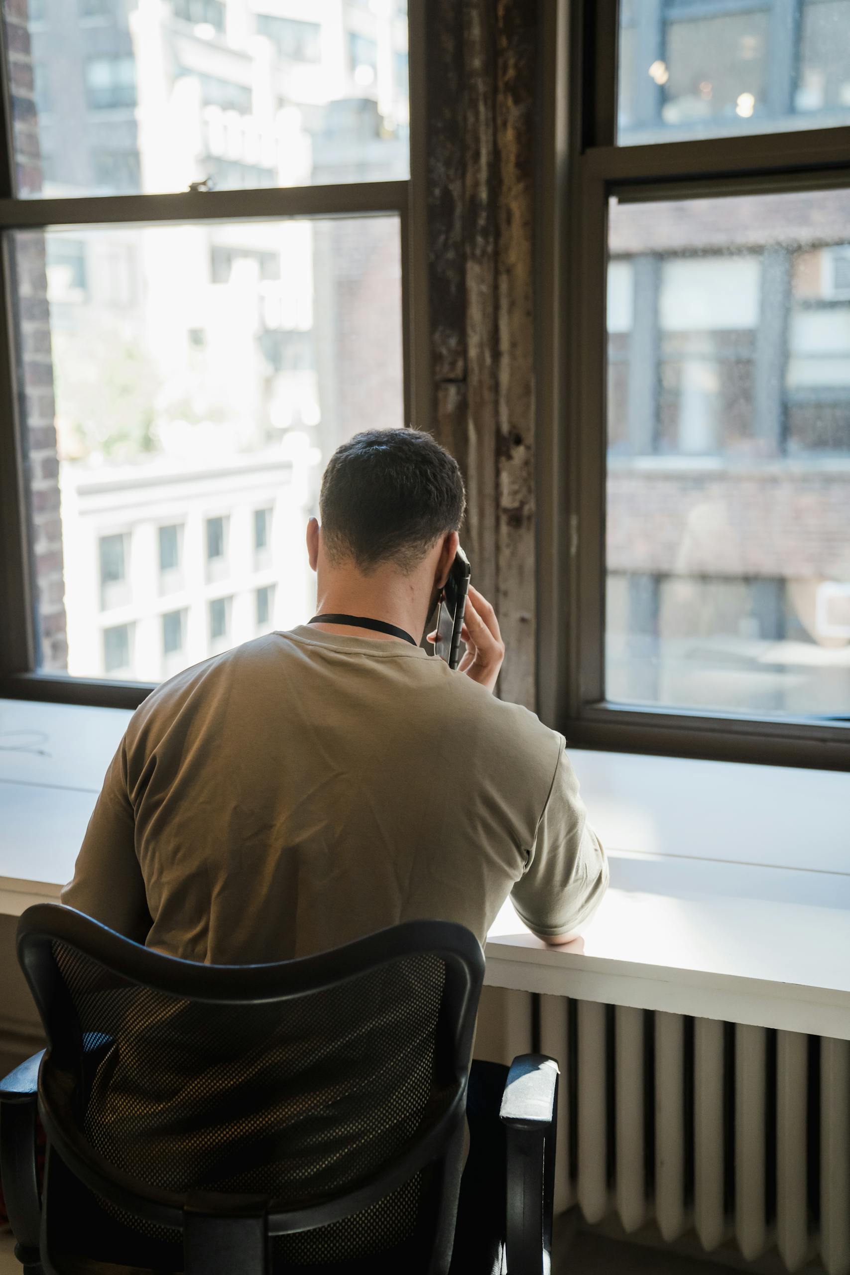 Businessman making call in an urban office setting overlooking cityscape.